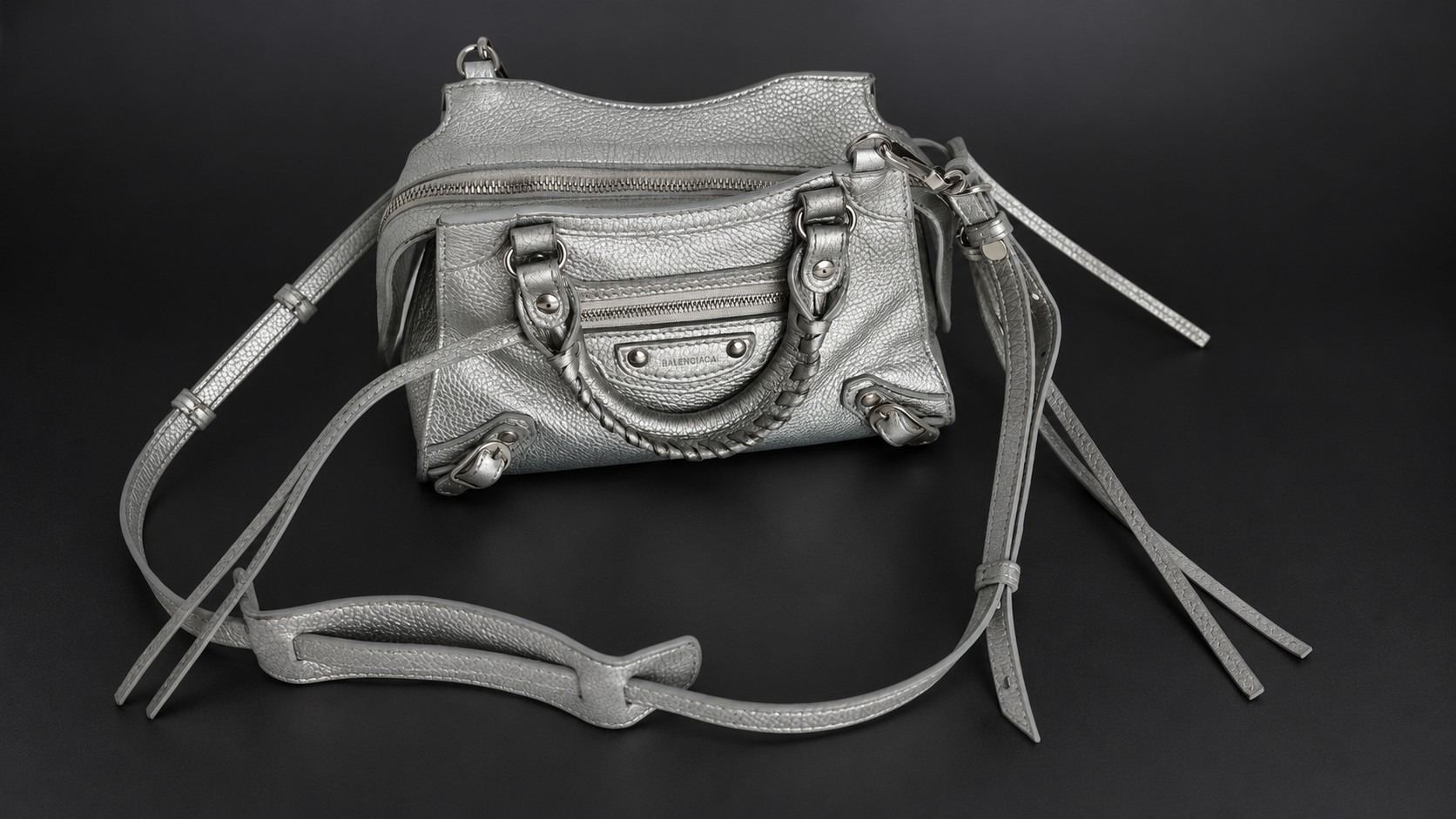 Серебристая сумка Balenciaga Neo Classic City Mini с плечевым ремешком на тёмном фоне